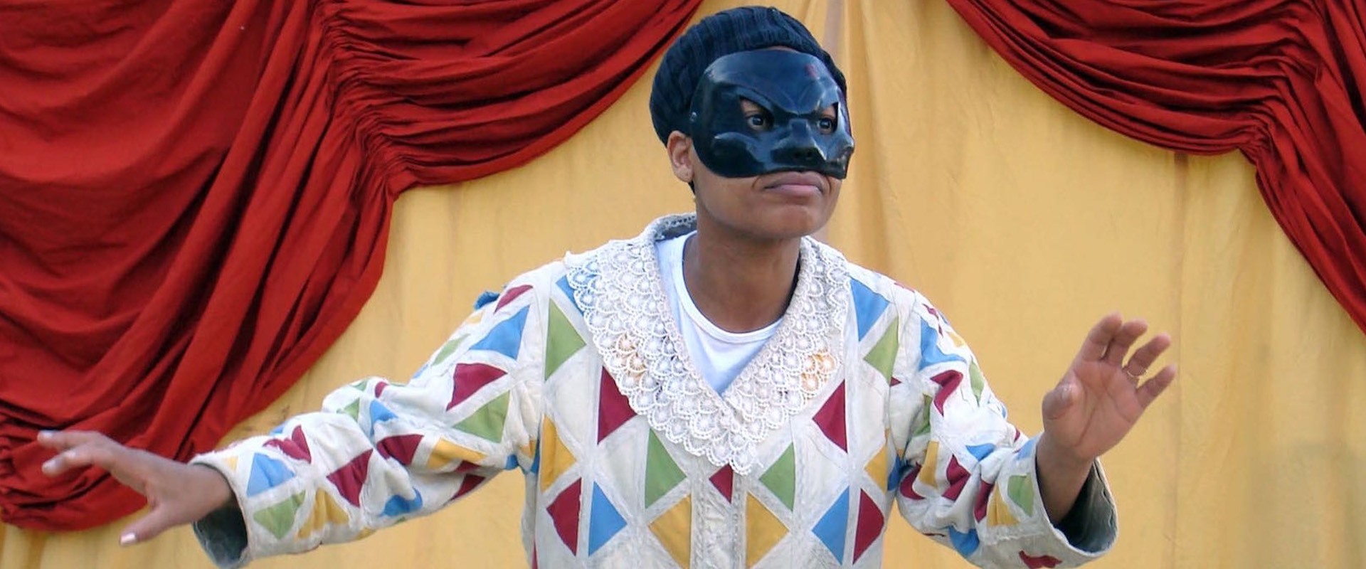 un homme joue sur scène avec un masque de commedia dell'Arte
